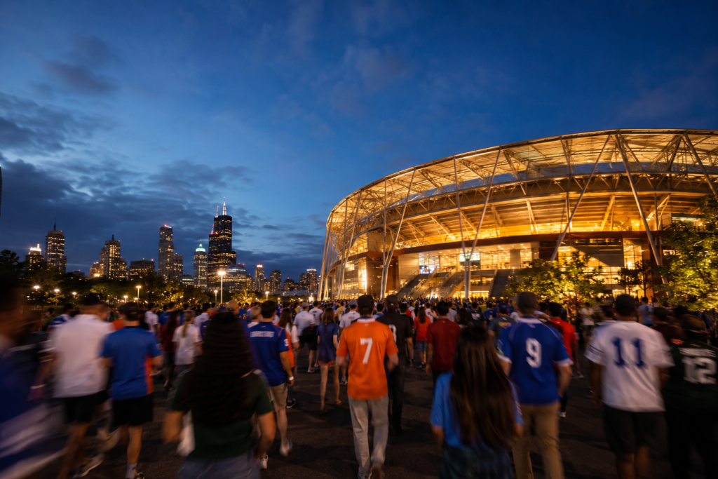 Guide to planning event travel itineraries — excited fans walking toward an illuminated stadium entrance at dusk representing the event travel planning experience