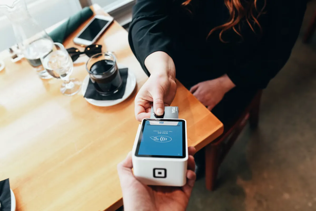 Customer holds a bank card above a contactless payment terminal